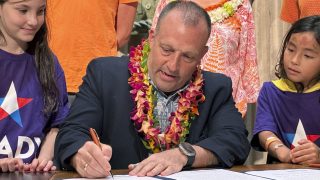 Hawaii Gov. Josh Green signs gun control legislation in Honolulu on Friday, June 2, 2023 as Leia Kandell, left, age 10, and Cole Kandell, age 7, look on.